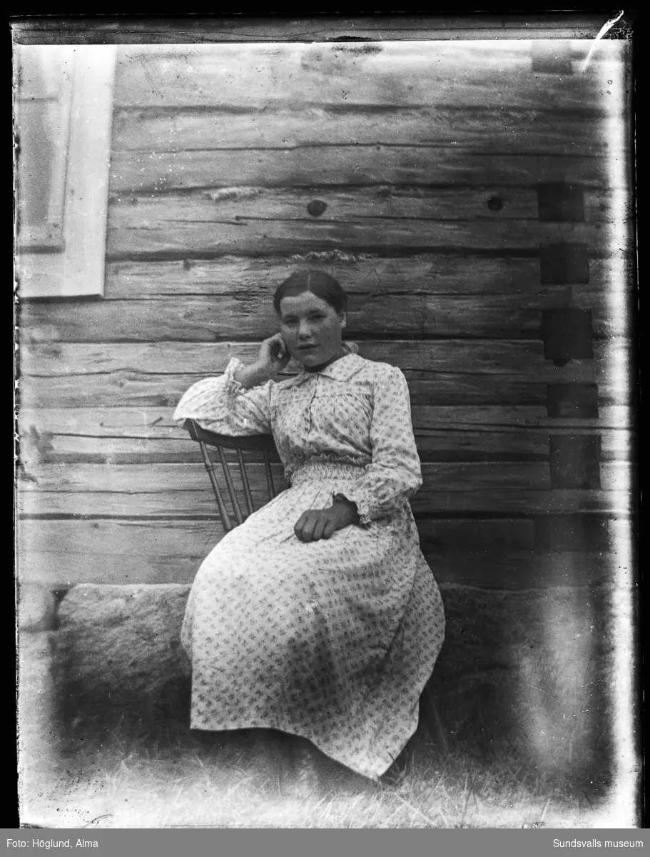 Porträttbild av en ung kvinna invid en timmervägg.
