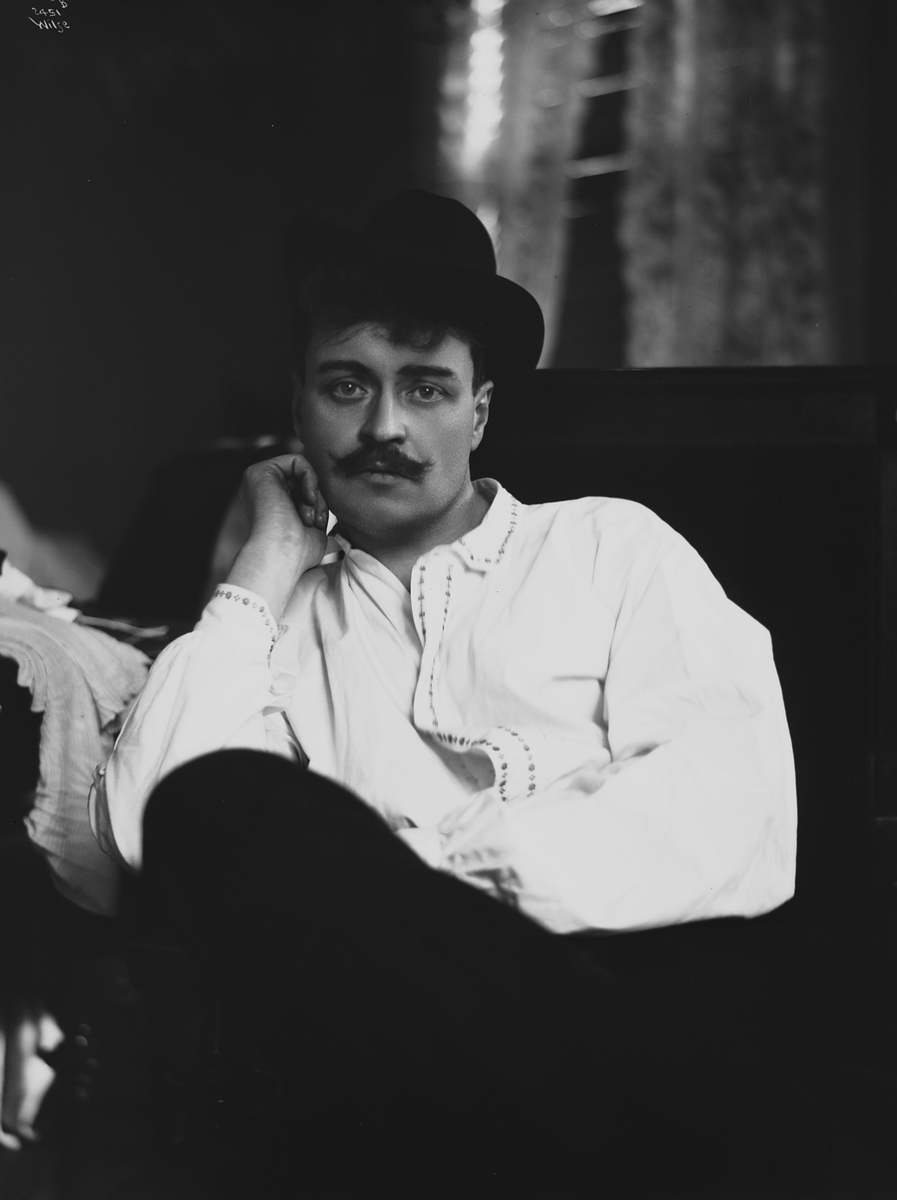 Skuespiller Jacobsen i hvit skjorte og hatt på hodet.