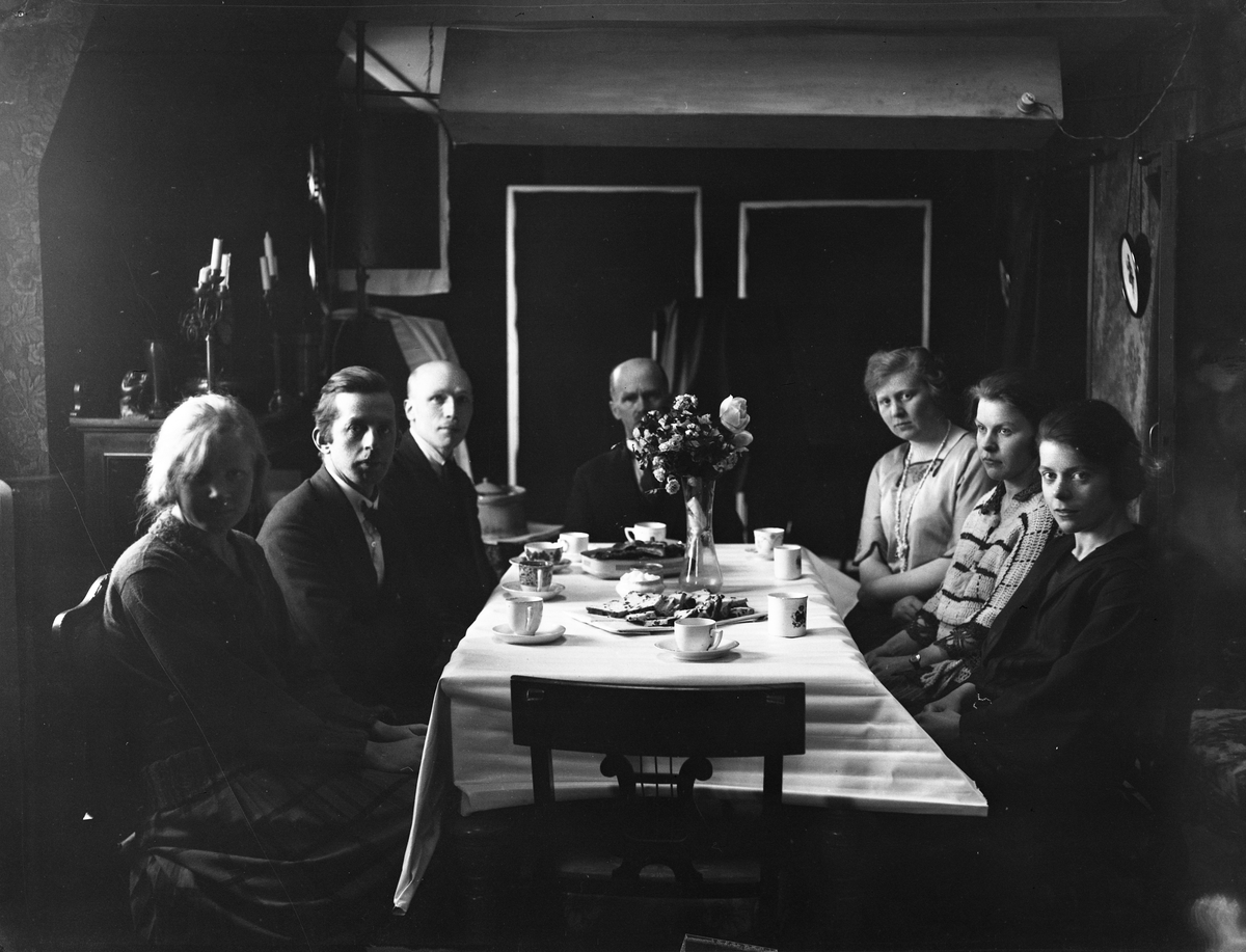 Kvinner og menn sitter rundt et dekket bord på kontoret på julaften. Fotografert 1923.