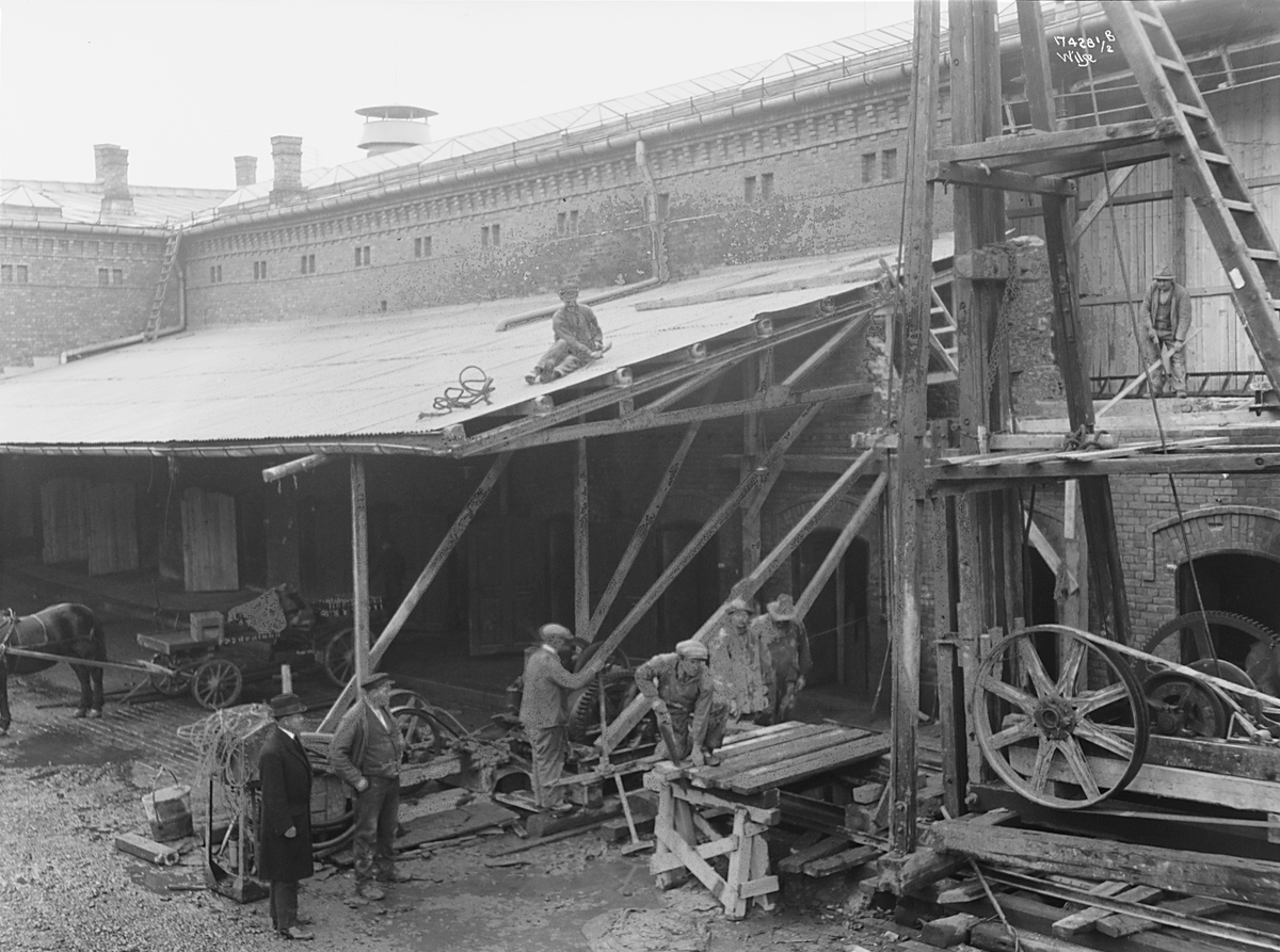 Flere arbeidere river og bygger nytt, mann med hatt ser på, Frydenlunds bryggeri. Fotografert 1923.