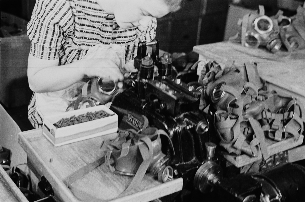 Kvinnelig arbeider ved gassmaskeproduksjonen ved Askim Gummivarefabrikk. Fotografert 1940.