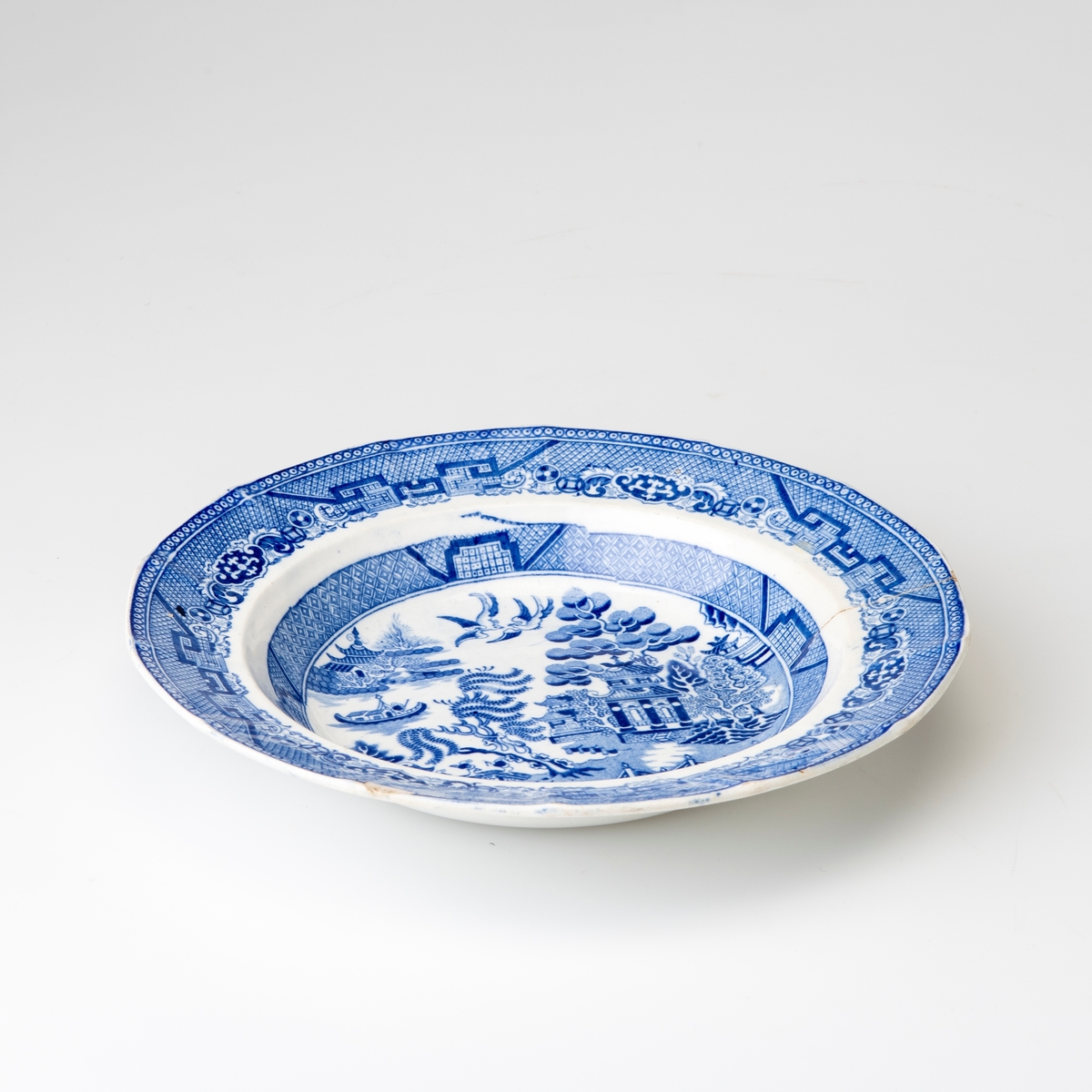 Dyp tallerken med mønsteret "Blue Willow", også kalt "China", i blått på hvit bunn.