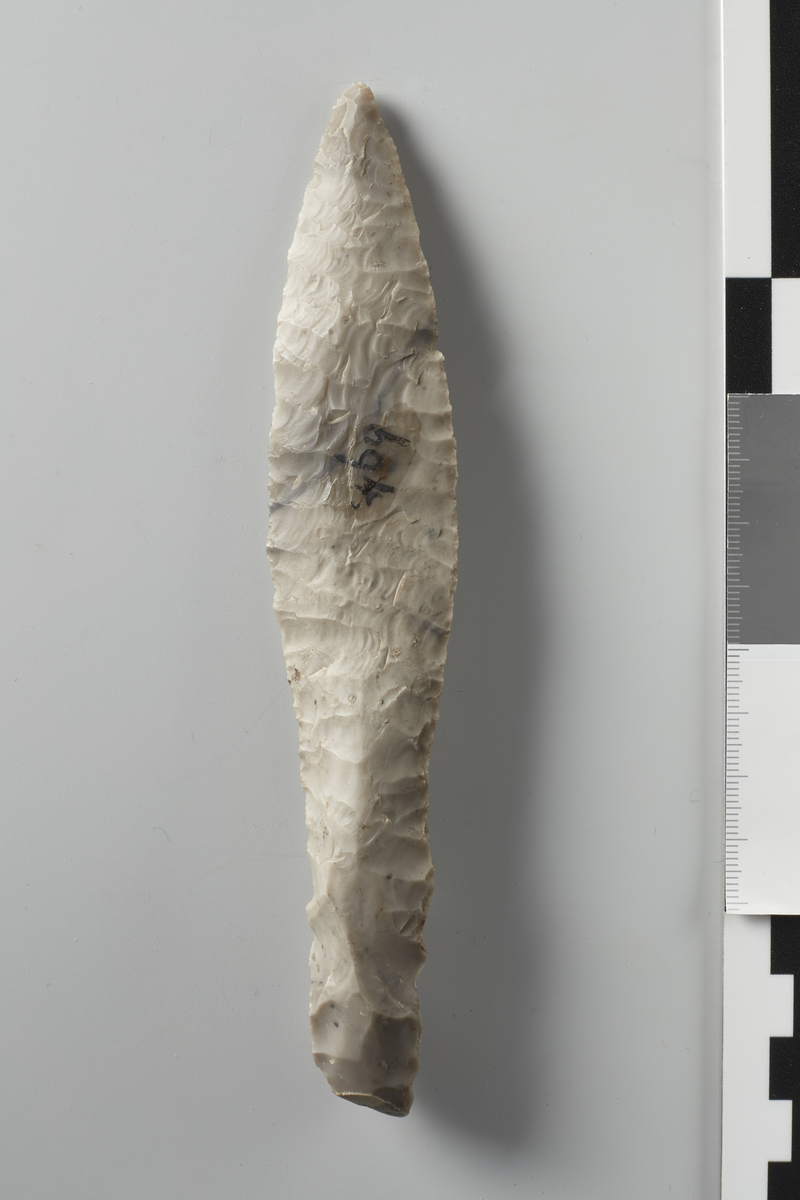 En Flintkniv; med Haandfang; Længde 6 Tr.; Bladet omtrent 4 Tr., bredest 11/4 T., tveegget; Formen i det Hele som ved No. 244.