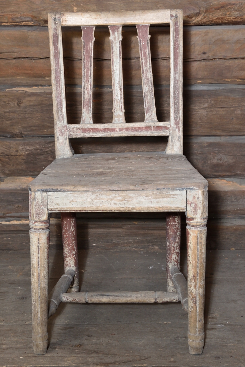 Stol tillverkad i trä. Rektangulär ryggbricka, delvis genombruten med tre spjälor. Enkel ostoppad sits. Stolen står på fyra rundsvarvade ben, ornerade med gles kannelyr. Mellan benen ett svarvat H-format benkryss. Stolen har tidigare varit målad rödbrun. 