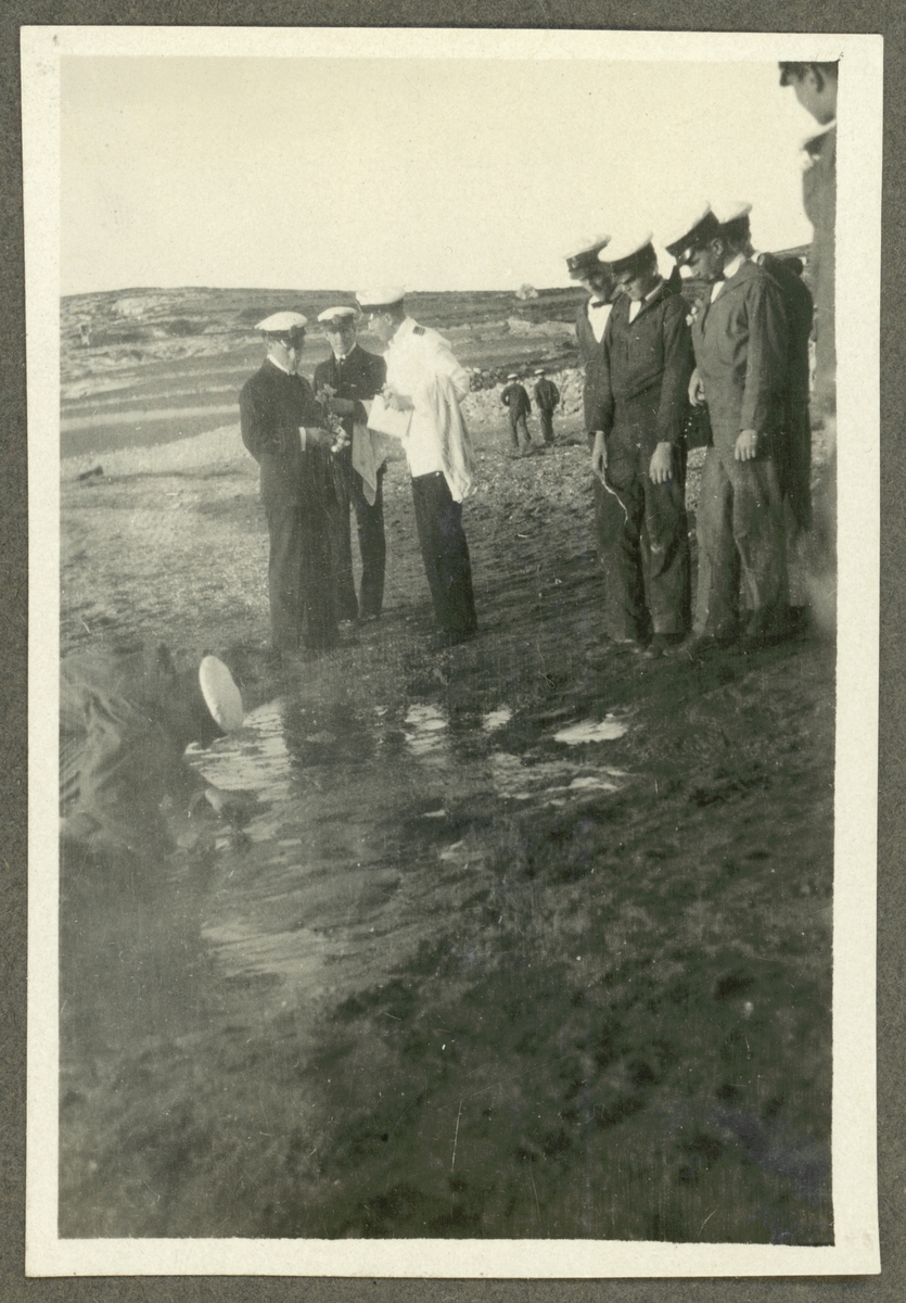 Bilden visar en grupp sjömän från Fylgia som intresserat tittar på hur en kamrat undersöker marken på Milos.