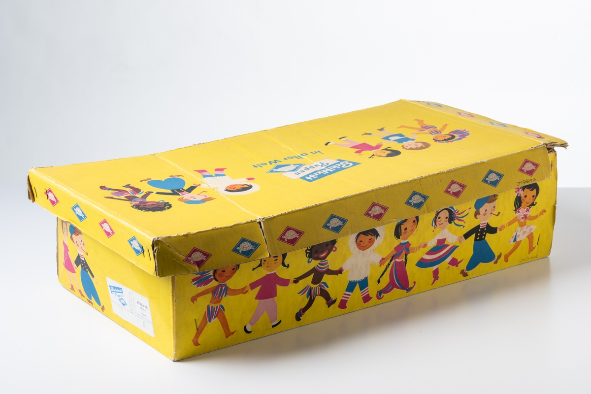 Originalkartong, låda med lock, till en så kallad Sköldpaddsdocka, JM.56864:1. Dockan är av märket Schildkröt Puppen, tillverkad av Schildkröt-Puppen, före detta Rheinische Gummi- und Celluloidfabrik, Tyskland. Vaumärket är en sköldpadda. 

Förpackning av gulfärgad wellpapp med tryckta illustrationer i flera färger i form av barnfigurer från hela världen. Lådans öppning har en vågig kant. På lådan tryckt text: ”Schildkröt Puppen 8706w/56 ’Mama’ 1 Stück Made in Western Germany”, och ”Tortoise Dolls all over the word”, "Tortue Poupées dans tout le monde”. På locket tryckt text: “Schildkröt Puppen in aller Welt”. Kartongen har skador.

Se vidare Historik.