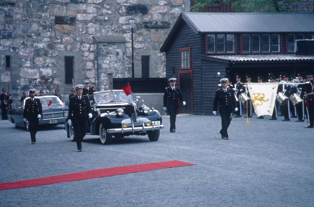 KOngen og dronningen i åpen bil på vei til signingen i Nidarosdomen under politieskorte.