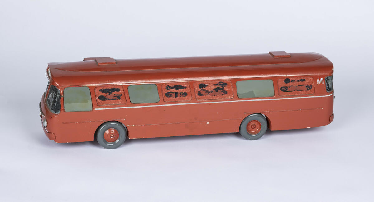 Tremodell av Oslo Sporveiers buss A-15730. Modellen er malt rød, med en hvit stripe langs siden. Bussen har detaljerte utskjæringer for dører og vinduer, og detaljer på taket. 