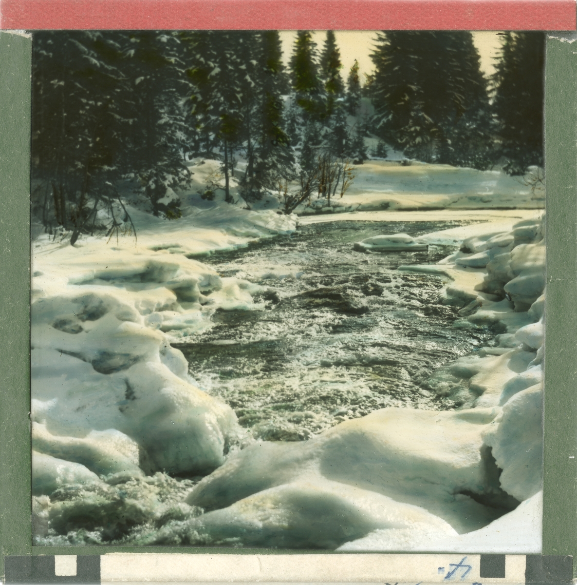 Håndkolorert dias. En liten elv renner gjennom et snødekt skogslandskap.