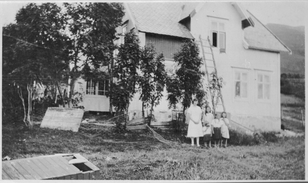 Kvinne og fire barn foran hus i Grovfjord.