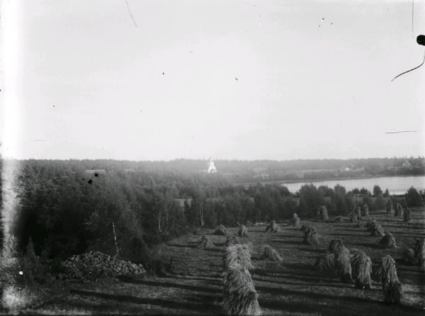 Drängssjön och Drängsereds kyrka sett från Sjöbol. I förgrunden åkrar med höstackar.