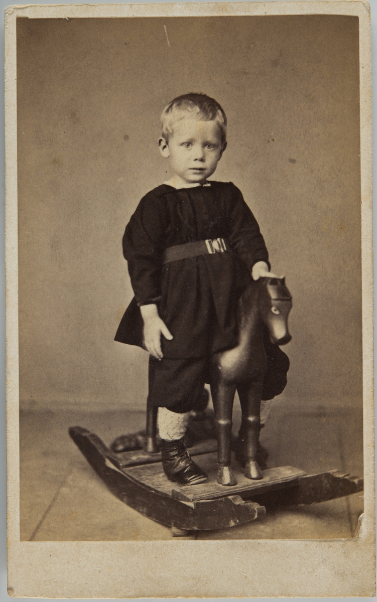 Portrett av liten gutt på gyngehest.