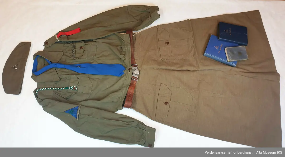 Speideruniform fra 1950-tallet komplett med jakke med påsydde stjerner og troppsnavn, skjørt, belte, snor til fløyte, lue med emblem, slips med emblem, håndbøker og sangbok.