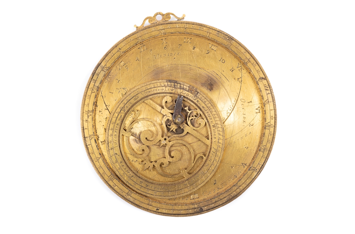 Astrolabium av förgylld metall, med inskriptioner på tyska. På framsidan inom cirkelrund kant, excentrisk rörlig genombruten zodiakring, samt fragment av diopterlinjal av järn. På baksidan månkalendarium med två rörliga skivor.