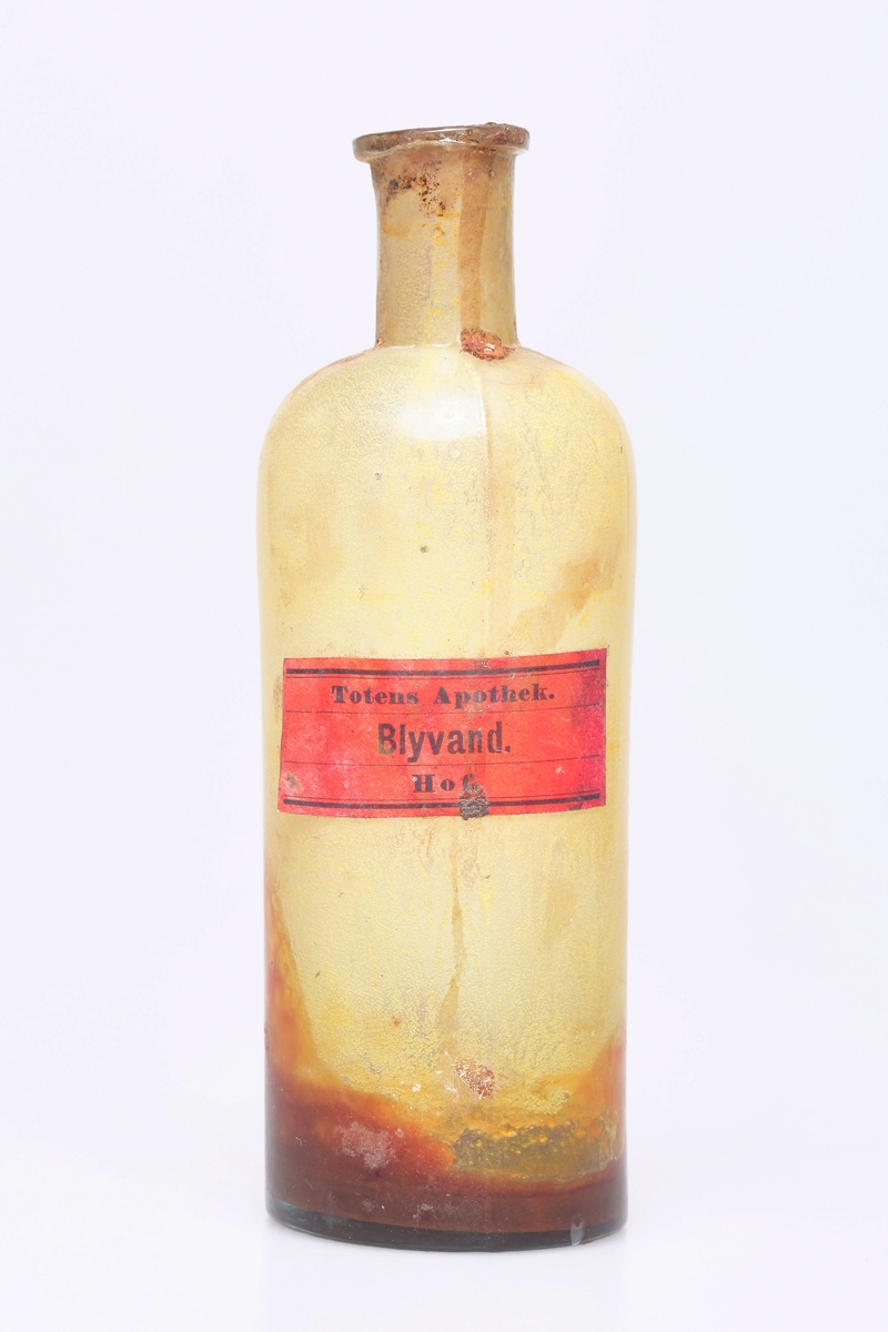 Flaske med inskripsjon: Blyvand. Blyvann er en blanding av 1 del blyeddik til 49 deler vann som tidligere var mye brukt til omslag etter støt, ved overflatesår, og lignende.