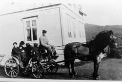 Hest med karjol på gårdstun i Kasfjord. Kusk og passasjerer 