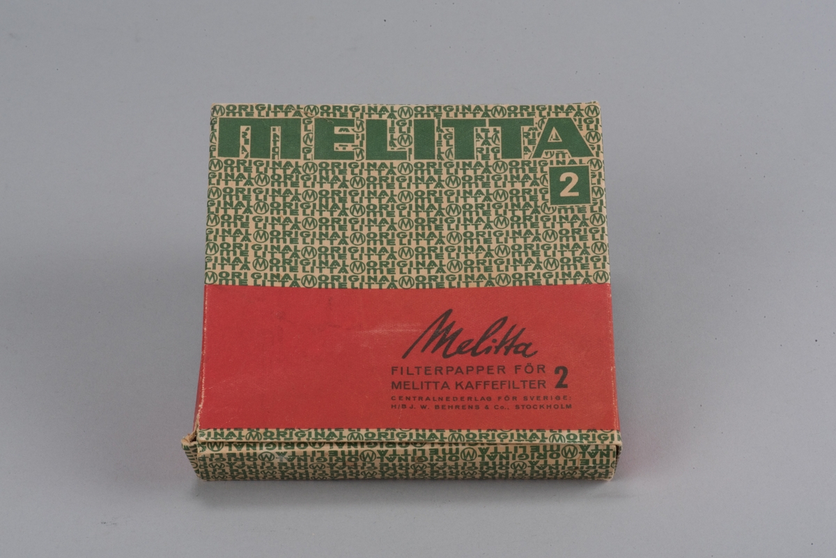 Förpackning för kaffefilter i kartong i rött och grönt. Text på förpackningen: "Melitta filterpapper för melitta kaffefilter 2". I förpackningen finns runda filter kvar.