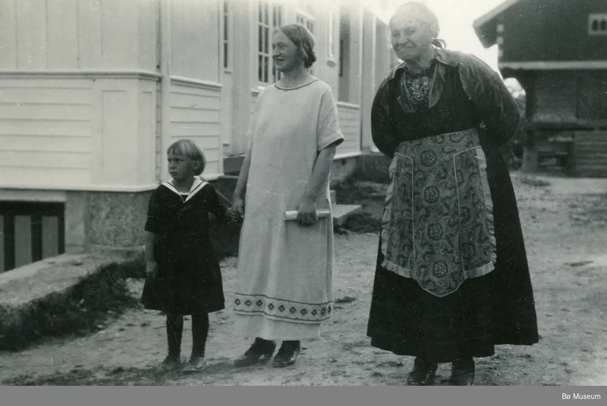 Kvinner i tre generasjonar på tunet på Valen.  Ingebjørg Valen (f. Vaa) med ei av døtrene. Svigermor Anne Ramse gift Valen til høgre.