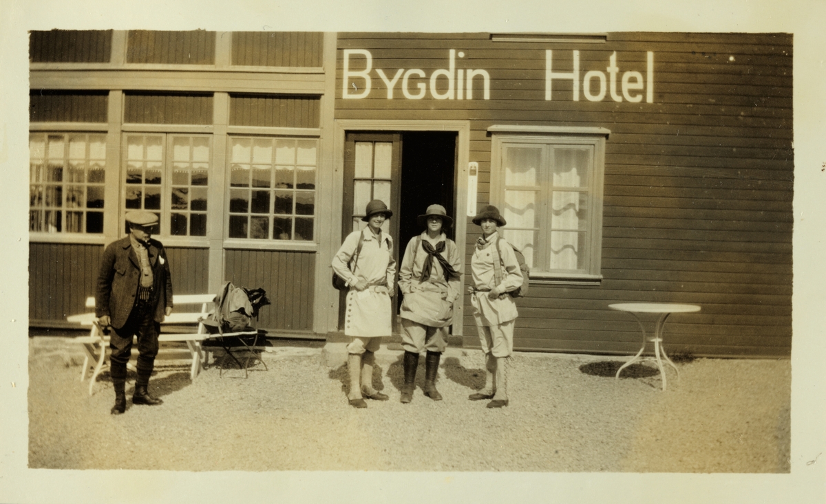 Lucy Egeberg, Sisken Skjelderup og Mimi Egeberg foran Bygdin Hotel, klare til å starte på fottur i Jotunheimen. Til venstre ukjent mann. Fotografert juli 1926.
