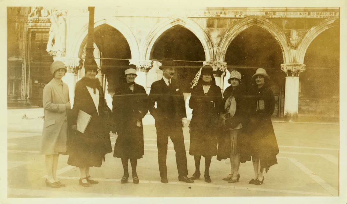 En gruppe turister, seks kvinner og én mann, på Piazza San Marco i Venezia. Blant kvinnene er antagelig Nini Egeberg og døtrene Mimi, Lucy og Karen. Fotografert påsken 1927.
