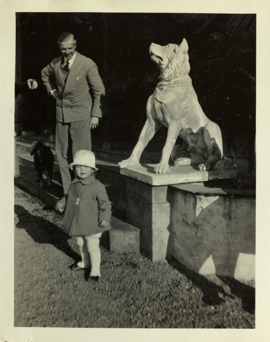 En mann, antagelig Anton Fredrik Klaveness, og niesen "Lalingen" foran en skulptur av en ulv ved inngangen til eiendommen Lagåsen i Bærum. Fotografert juni 1928.