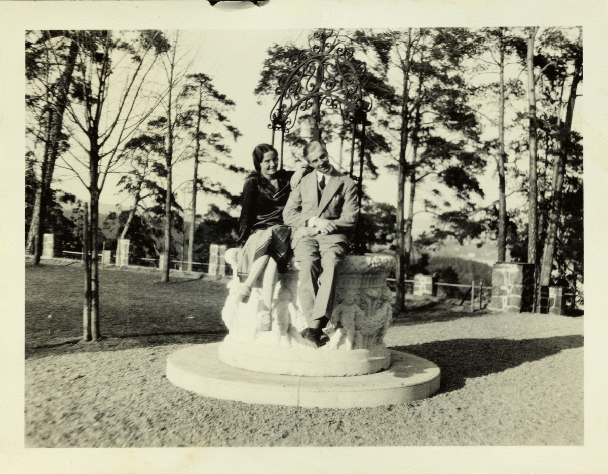 Et ungt par, antagelig Lucy Egeberg og forloveden Anton Fredrik Klaveness, sitter på en steinskulptur på eiendommen Lagåsen i Bærum. Fotografert juni 1928.