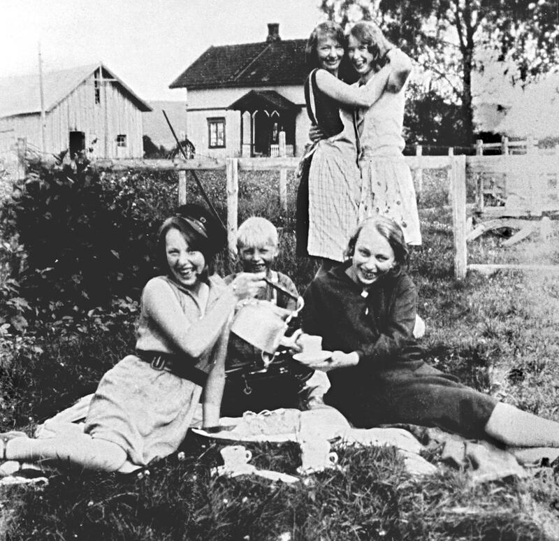 Foto av kvinner og barn som har piknik i en hage.