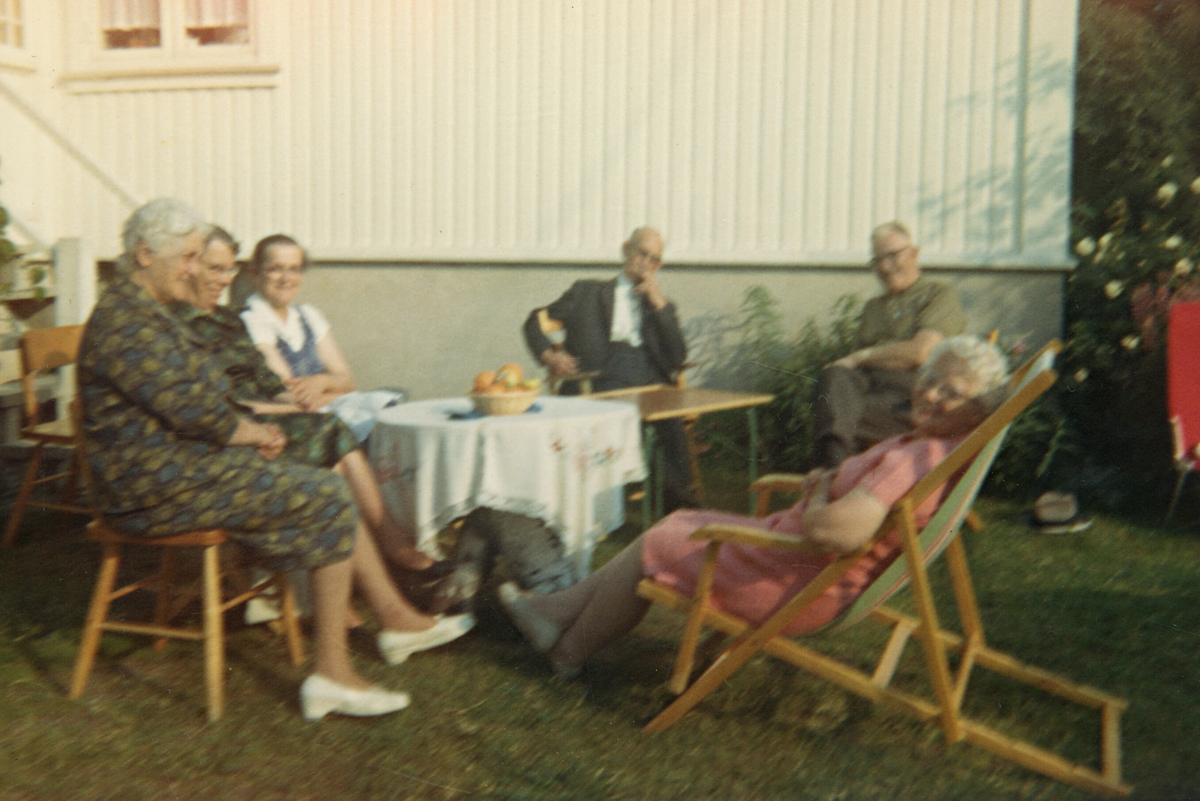 Samling av eldre folk rundt eit bord i hagen.  Nr. tre f.v er Astrid Margrete Terjesen.