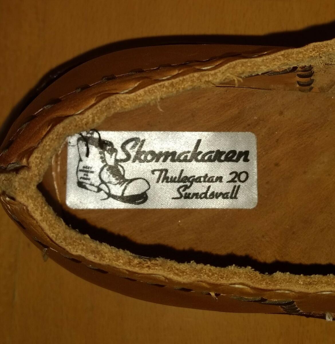 Gåva av skomakarmästare Mogens Hansen, Sundsvall. " Skomakaren, Thulegatan 20, Sundsvall " på etikett inuti varje sko, storlek 38. Modell från c:a 1800 -talet. Mellansula och klack är gjord av näver. Plac: M4BF2.