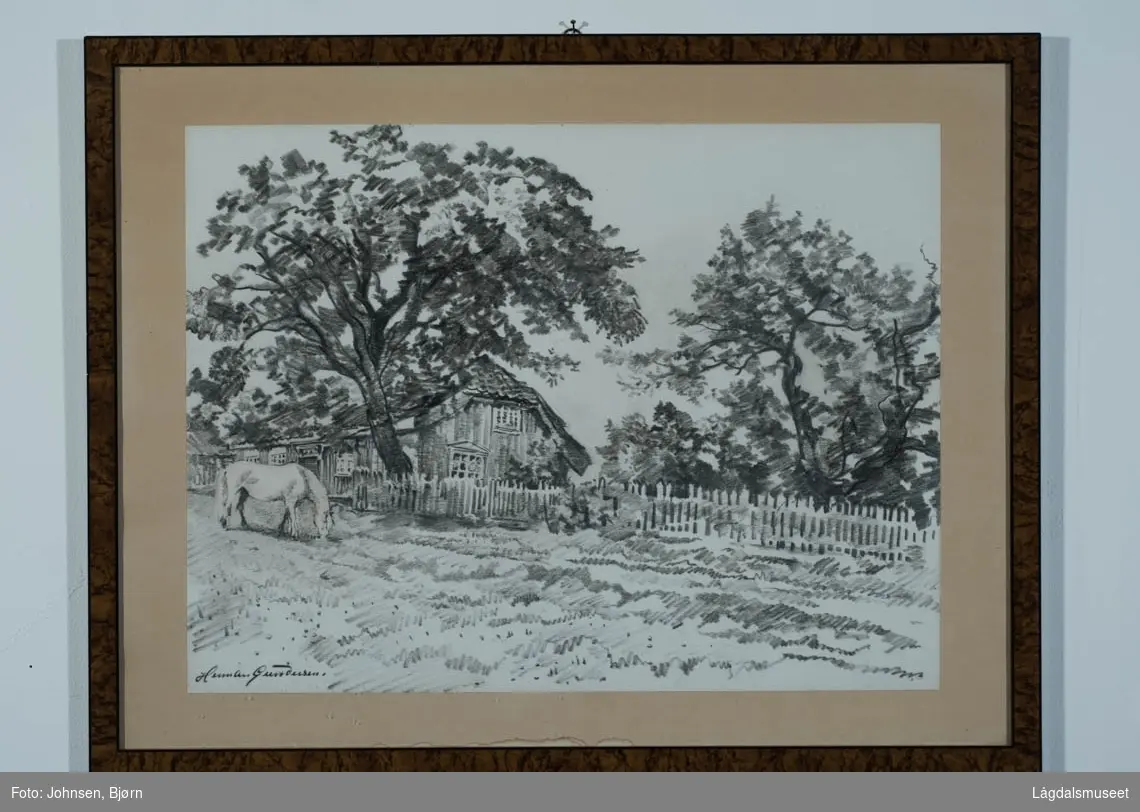 Motivet viser en beitende hest foran et stakittgjerde.  Bak gjerdet og bak et stort løvtre ses et hus.