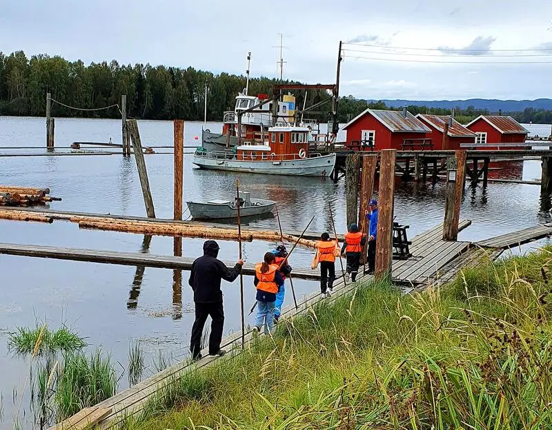 Foto av barn med redningsvest og fløterhaker som skal ut på vannet og fløte tømmer