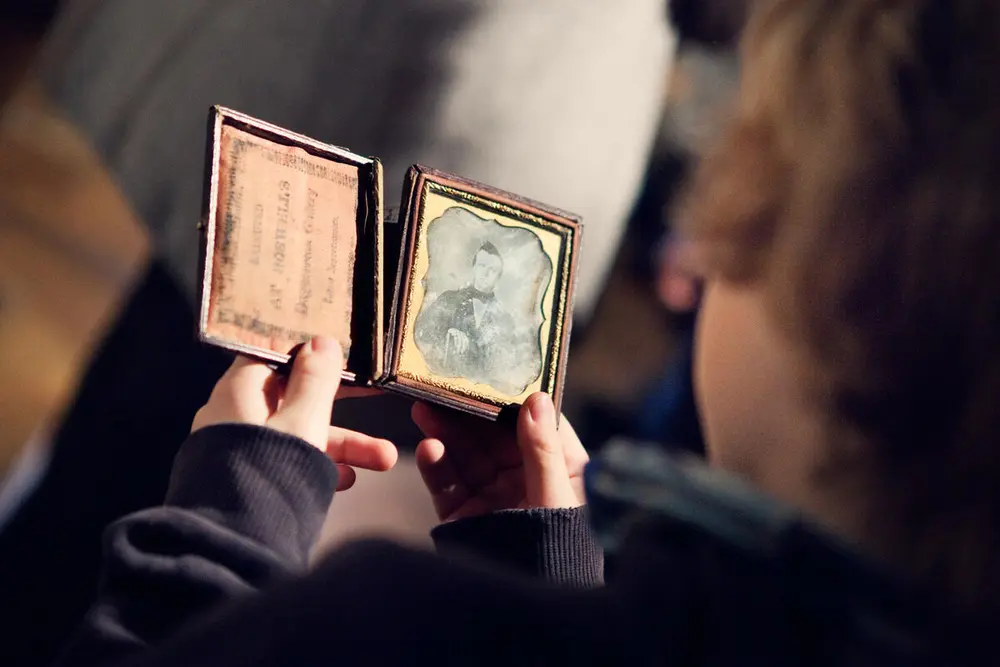 A schoolboy holds a daguerreotype in his hands.