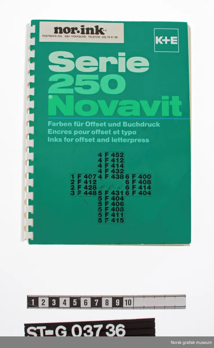 Produktkatalog med plastspiral og blågrønt omslag med glanset overflate. Katalogen viser ulike trykkfarger fra produsenten K+E av produkttypen Serie 250 Novavit for offset og boktrykk. 

På forsiden er det påklistret et merke med med logoen til firmaet "Nor ink" med adresse Hokksund.