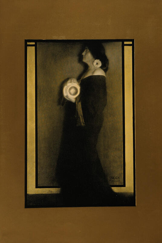 Dust fotografi av kvinne i lang sort kjole, i profil en gullramme er påmalt fotografiet.