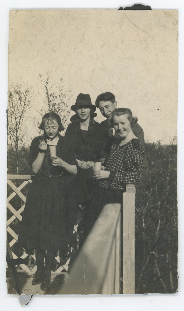 Tre unge kvinner og en mann spiser eggedosis på en veranda.