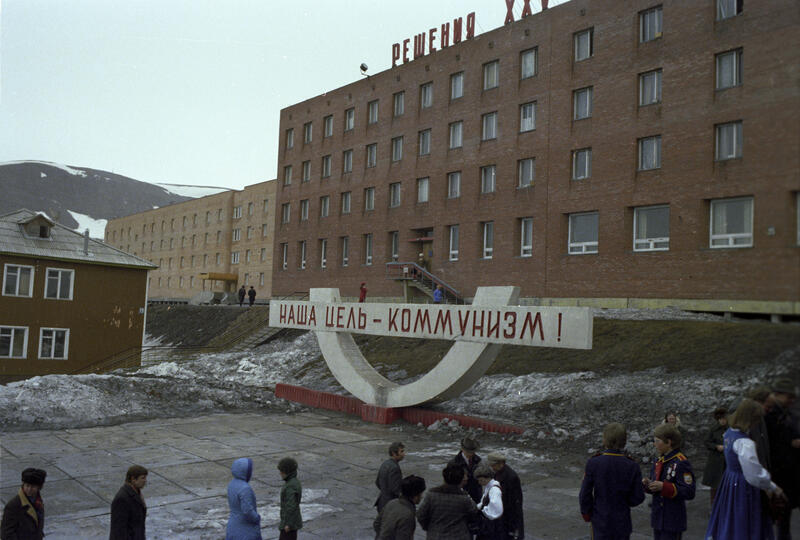 Bildet av kulturhuset i Barentsburg. Foran står et skilt med teksten " Vårt mål - kommunisme" på russisk.