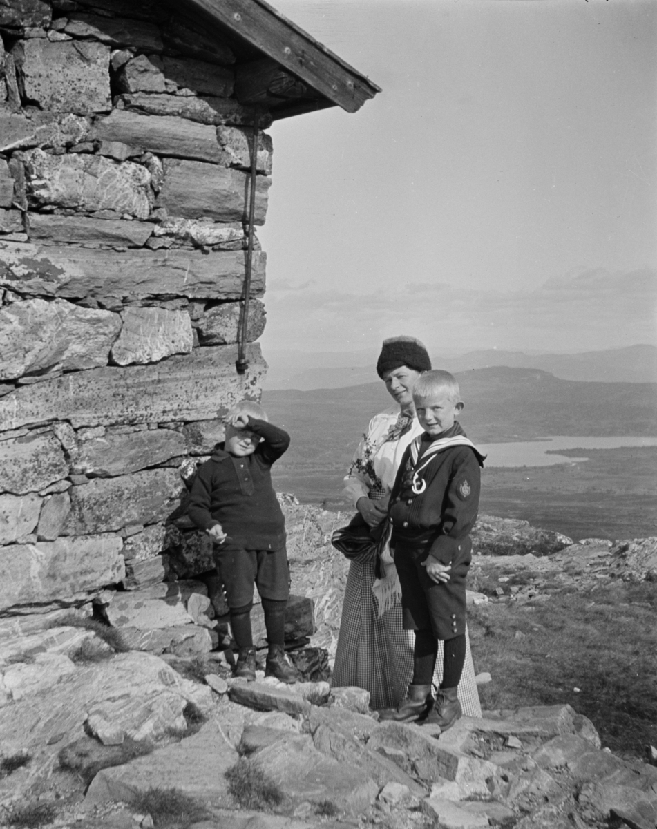 To små gutter og en kvinne ved hytta på toppen av Skeikampen.