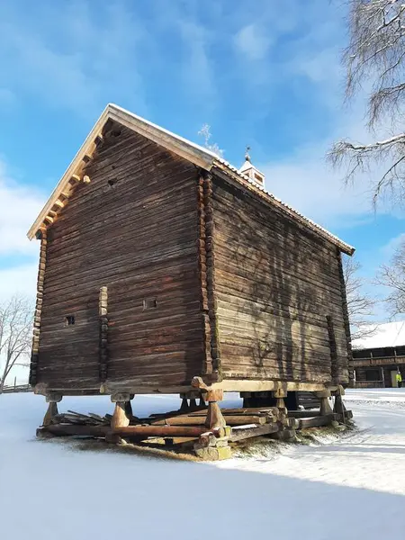 Bildet viser et stabbur. Bildet er tatt fra baksiden av bua. Det er snø på bakken.