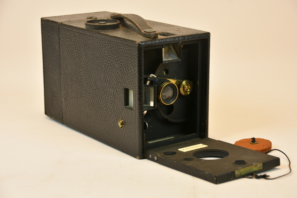 Lådkamera Kodak Junior No. 3. Objektivskydd av filt. Magasin för rullfilm, 100 exponeringar. För att ställa in exponeringstiden och bländare fälldes fronten fram med hjälp av den lilla öglan.
Lös skruv medföljer.
