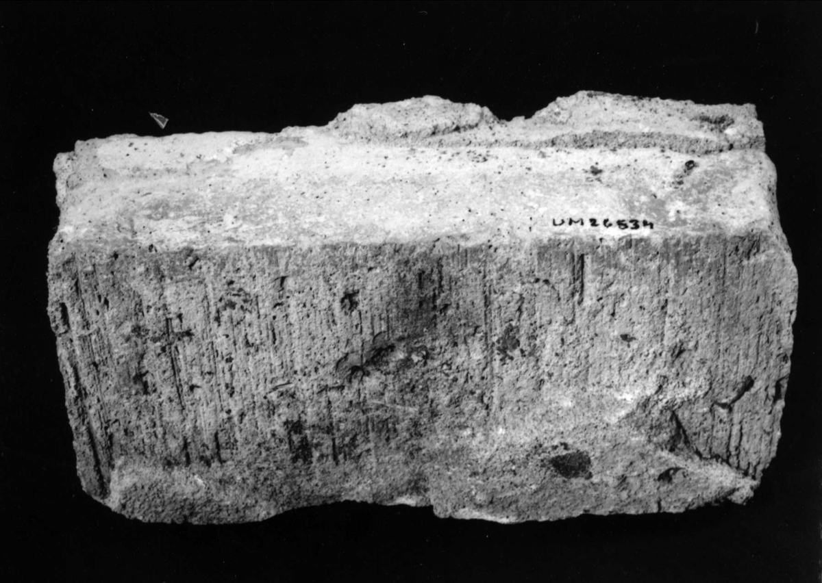 Tegelsten av rödbränd lera, med rester av murbruk, stämplad på ena kortsidan: U E 16.