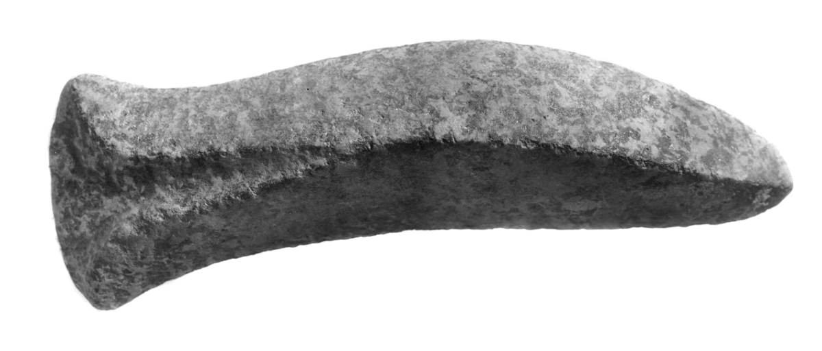 "Rhombisk øks av spettet sten (Saussuritgabbro), meget nær R. 39 fra Opedal, Ullensvang. Paa foreliggende eksemplar er dog tversnittet helt kvadratisk og det uthulede parti op fra eggen dypere end paa citerte figur hos Rygh. Hel og av udmerket soigneret arbeide. Skafthullet er ikke paabegyndt. Længde 24,9 cm. " 