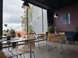 Interiørbilde fra Kafe Standpunkt viser bord og stoler opp mot et vindu som går fra gulv til tak