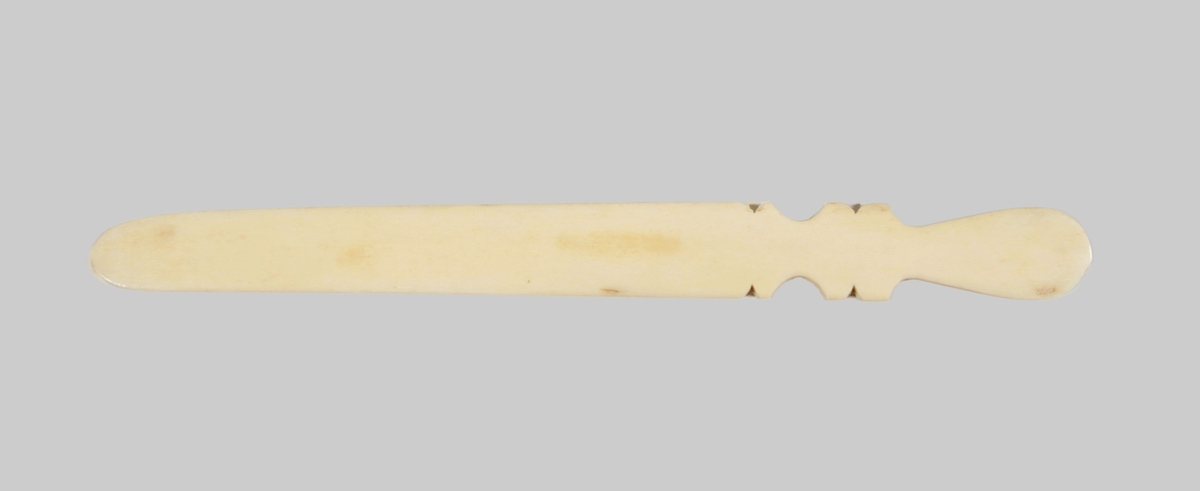 Papperskniv i ben. Platt, med profilerat kort handtag och långt blad.

Funktion: För att sprätta upp kuvert
