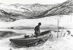 Petter Nilsen Kuljok måker båten, som ligger på land ved Lan