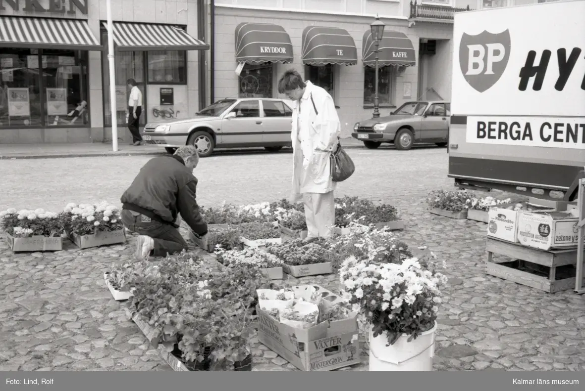 Torghandel på Stortorget i Kalmar. Blomsterförsäljare betjänar en kund.
