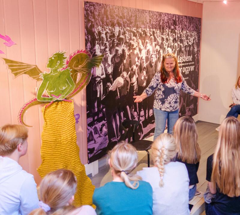 Inge Ås står foran en gruppe barn og formidler i utstillingen.
