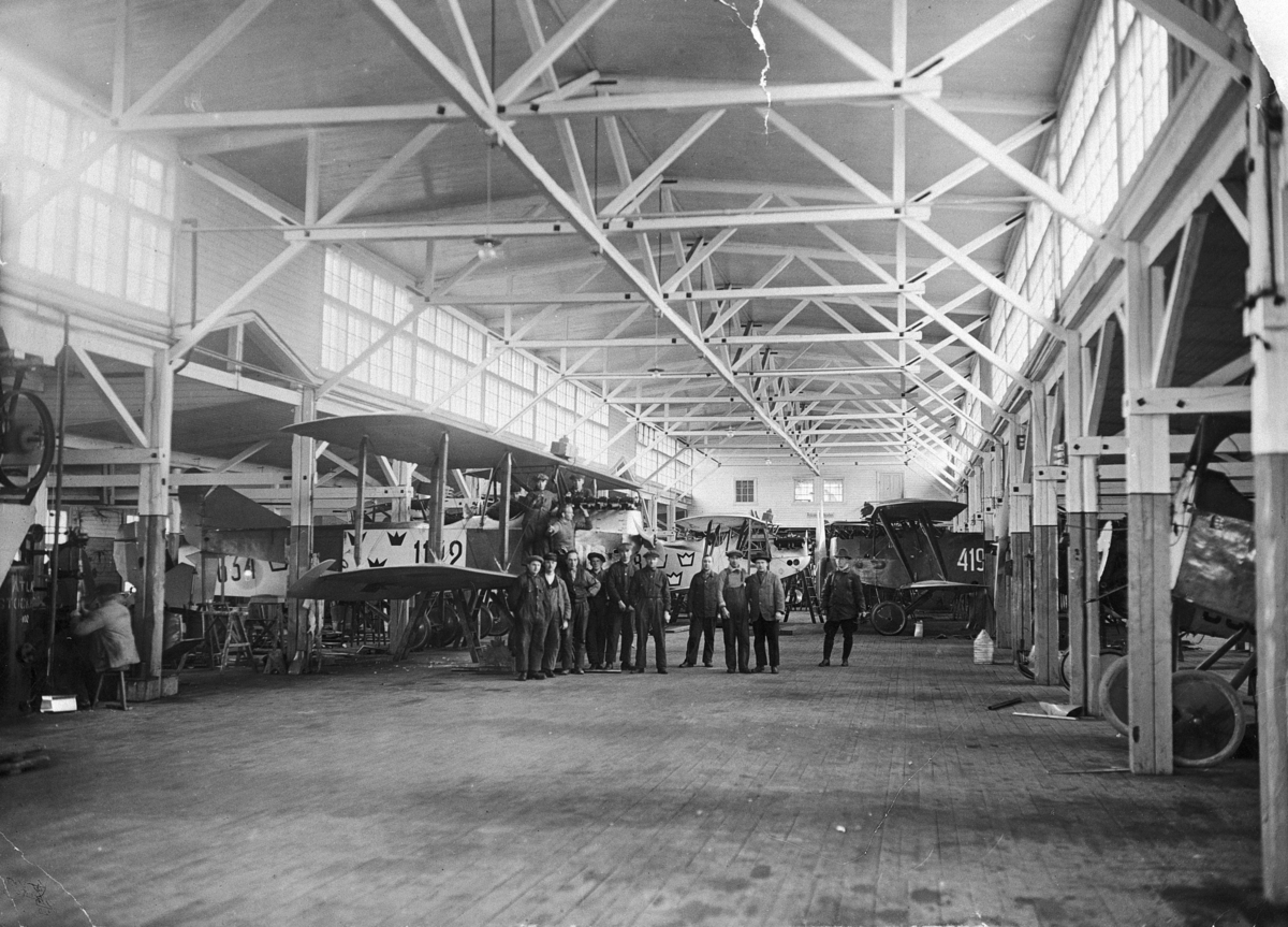 Interiör från monteringshallen på Flygkompaniets verkstäder omkring 1920-1926. Personal står framför flygplan FVM Albatros 160 och FVM Phönix Dront.