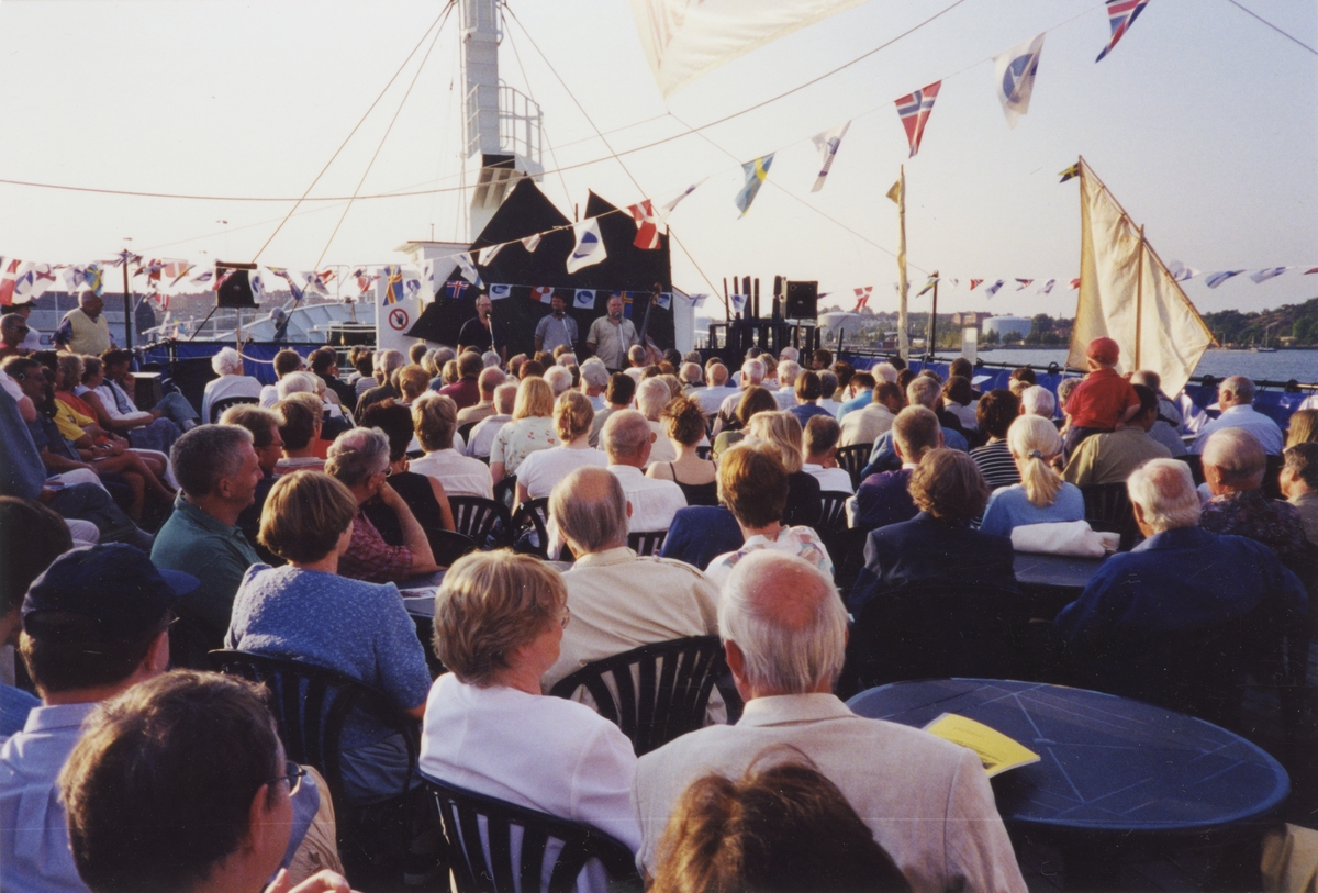 Utställningen Människor och båtar i Norden. Tre stycken talare samt ett publikhav på däcket av fartyget m/s NORDWEST.