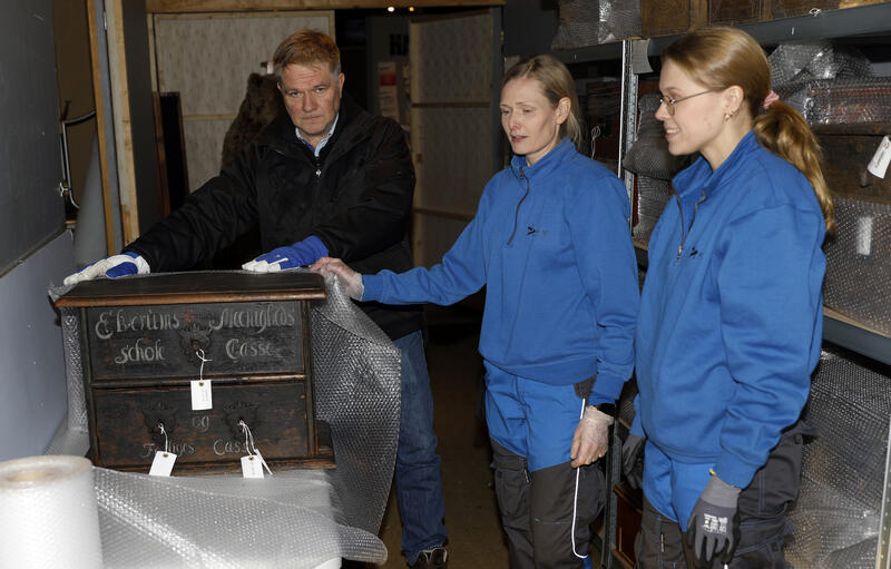 Tre museumsarbeidere avbildet sammen med en kiste fra gjenstandssamlingen på Glomdalsmuseet.