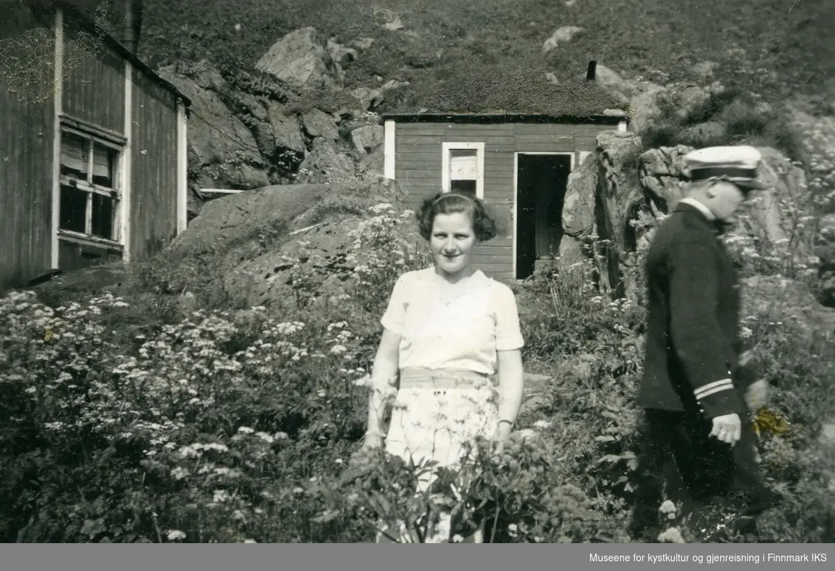 Sylvie Pedersen foran en del av bebyggelsen i Hornvika. Mannen er ukjent. 1938.